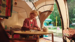 Een foto van een meisje dat in een tent aan een tafeltje aan het kleuren is