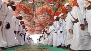 Foto van twee rijen met mannen gekleed in het wit die dansen 