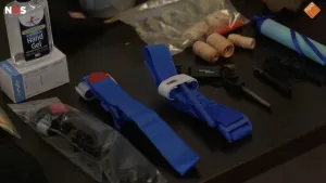 Foto van de inhoud van een noodpakket met onder andere handgel, tape en banden.