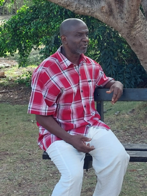 Een foto van twee mensen op een bankje onder een boom, links een man, rechts een vrouw.