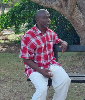 Een foto van twee mensen op een bankje onder een boom, links een man, rechts een vrouw.