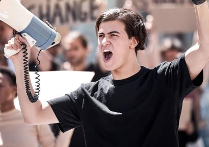 Foto van jongen met een megafoon die aan het roepen is. 