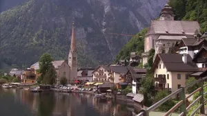 Een foto van een Oostenrijks landchap met een kerk en huizen aan de rand van een bergmeer, op de achtergrond bergen.