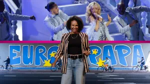 Presentatrice staat voor twee foto's. Bovenste foto is van een muziekoptreden, de onderste van graffiti.