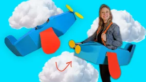 Foto van presentatrice Rosalie in zelfgemaakt vliegtuig van karton.