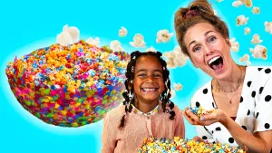 Foto van presentatrice Rosalie met kind en zelfgeknutselde bak met regenboogpopcorn.