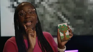 Een foto van presentatrice Tirsa die een blokkerige afbeelding van een boom vasthoudt, gemaakt met het speelgoed Ministeck.