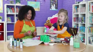 presentatrice en meisje zitten aan tafel te knutselen