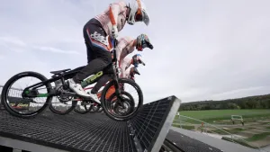 Een foto van vier mensen op kleine crossfietjes van opzij gezien. Ze staan op de pedalen, klaar voor de start. Ze dragen helmen en wedstrijdkleding.