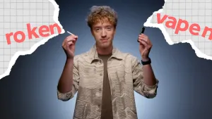 Presentator van NOS op 3 voor bluescreen met in de ene hand een sigaret en in de andere hand een vape.