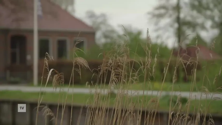 Een foto van een huis in De Knipe, op de voorgrond de vaart met wat begroeiiing.