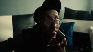 Jongen met pet en bril op kijkt ergens naar.