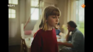 Meisje staat middenin beeld. Ze heeft blond haar en draagt een rode trui.