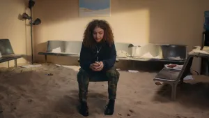 Meisje zit op een stoel middenin een kamer.