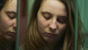 Meisje kijkt somber in de spiegel. Ze kijkt naar beneden.