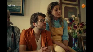 Twee mensen zitten naast elkaar in een woonkamer. Een man en een vrouw.