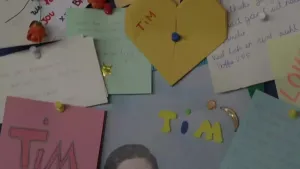 Een foto van een prikbord met allemaal briefjes aan Tim een scholier die overleden is.