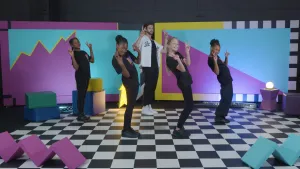 Foto van kinderen in zwarte kleren op geblokte ondergrond die dansmoves doen.