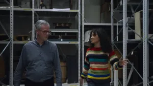 Een foto van presentatrice Serah en een man tussen stellingkasten.