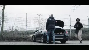 Thirsa draagt een kogelvrij vest en staat met een blij gezicht naast de politieauto, samen met een rechercheur.