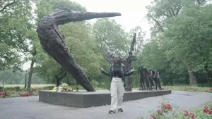 Presentator Thirsa staat in een park bij het slavernijmonument.