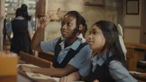 Een foto van twee meisjes in een schoollokaal in schooluniformen.