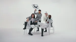 Foto van vier wit en zilver geklede jongens op witte achtergrond die in stoere houdigen poseren op stoelen.