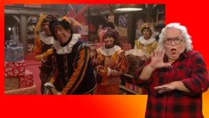 Pieten kijken verschrikt in het pakjesruim. Naast het scherm staat de gebarentolk.