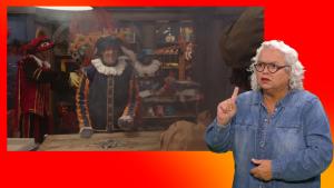 Pietje Paniek staat achter een tafel met puzzelstukjes. Naast het scherm staat een gebarentolk.