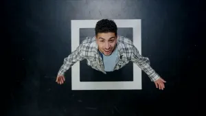 Een foto van presentator Nizar van bovenaf. Hij staat in een hokje dat met witte tape op de vloer gemaakt is.