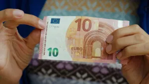 Foto van twee handen die een briefje van 10 euro vasthouden.