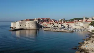 Een foto van een stad aan de kust van Kroatië, aan de waterkant staan huizen en een burcht.