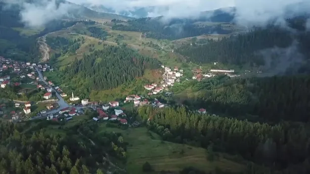 Een foto van een Bulgaars landschap met heuvels en daar tussenin in het dal een dorpje met witte huizen.