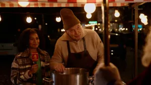 Stephanie staat naast een man die in de soep roert.