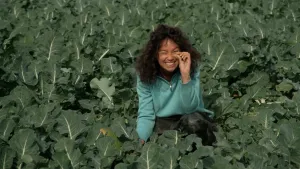 Presentatrice zit in een veld vol broccoli.