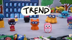 Foto uit stopmotionanimatie met speelgoedpoppetjes die allemaal dezelfde blauwe zonnebril dragen. Het woord trend staat er in hoofdletters bovenop.