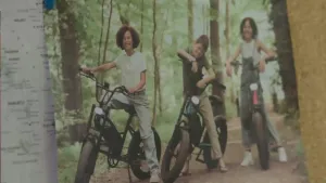Een foto van 3 kinderen op een fatbike, ze staan bij hun fietsen in het bos. Het is een foto die op een prikbord hangt.