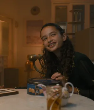 Een foto van een vrouw en een meisje aan een tafel, de vrouw heeft een hoofddoek om, ze kijken richting de camera.