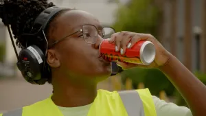 Foto van Klokhuispresentator Tirsa die een blikje cola drinkt.