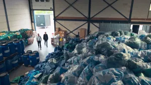 Twee mannen naast een gigantische berg met vuilniszakken