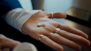 Foto van hand met twee witte pillen op de handpalm.