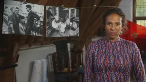 Presentatrice Astrid staat naast een lijn waarop twee zwart-wit foto's hangen.