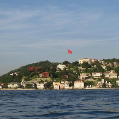 Een foto van water met daarachter land, waarop een Turkse vlag wappert.