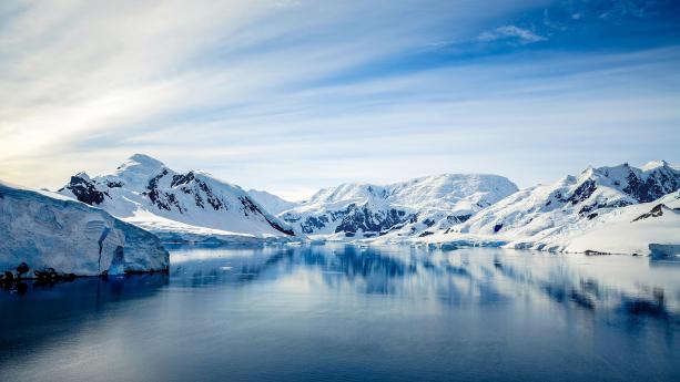 Foto van ijsbergen en ijs bij een blauwe lucht in Antarctica.