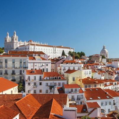 Foto van Portugese stad met witte gebouwen en oranje daken met een blauwe lucht. 