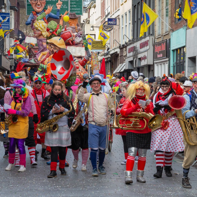 Foto van verklede mensen op straat tijdens carnaval die muziek maken. 
