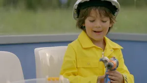 Foto van lachend jongetje met bouwhelm.