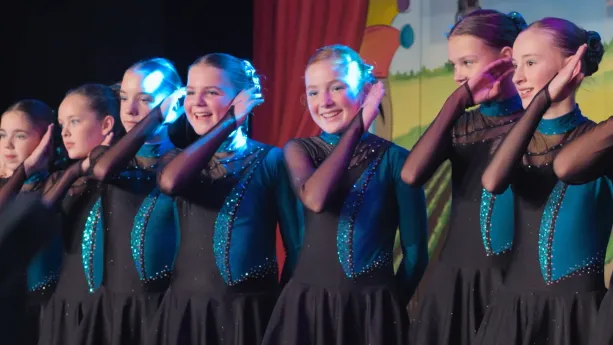 Foto van meisjes die in danskleding een dans opvoeren.