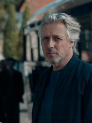 Foto van presentator Daan Schuurmans in stadssetting met bus op de achtergrond.