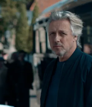 Foto van presentator Daan Schuurmans in stadssetting met bus op de achtergrond.